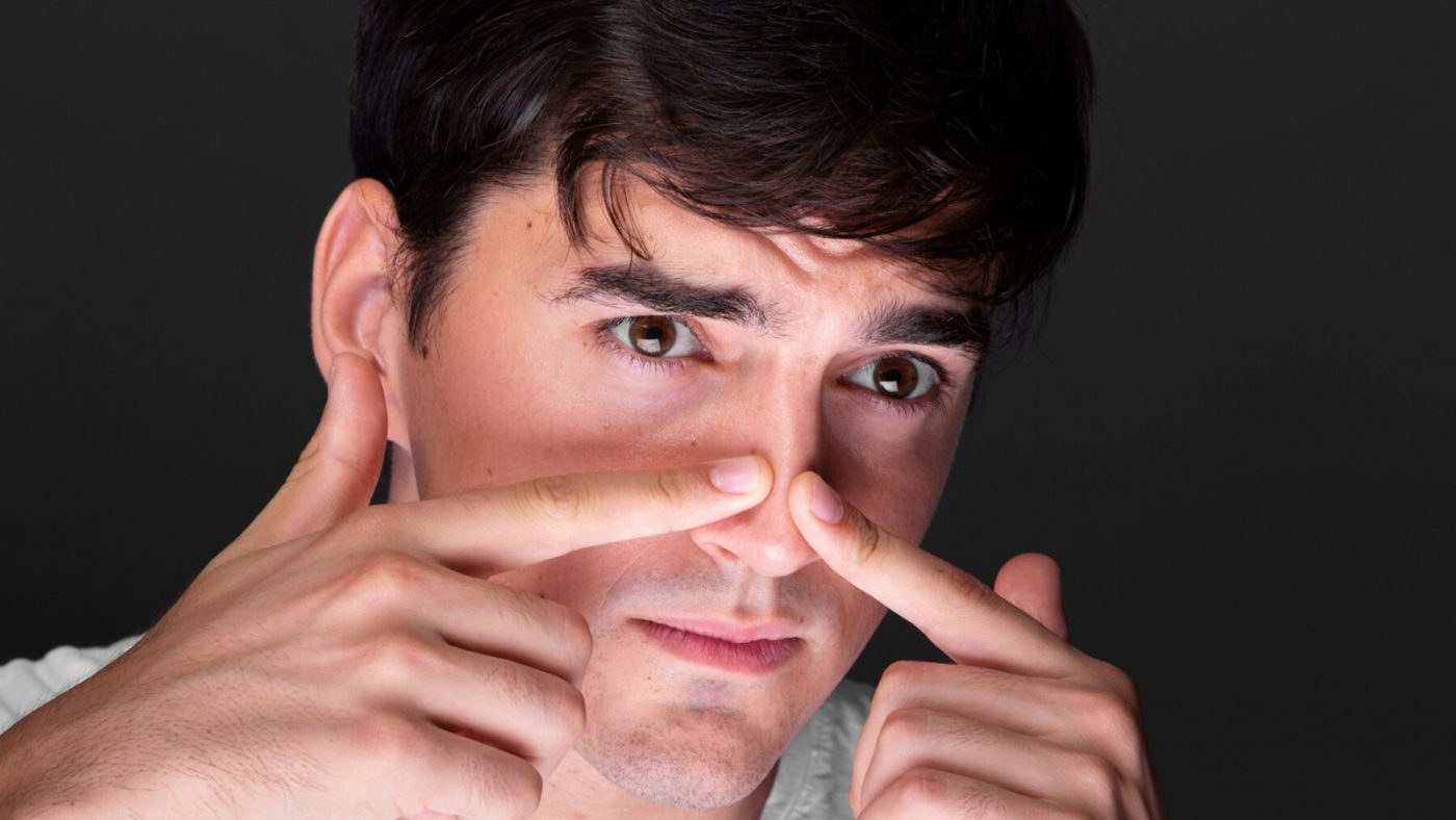 Seorang pria sedang memencet jerawat di hidung.